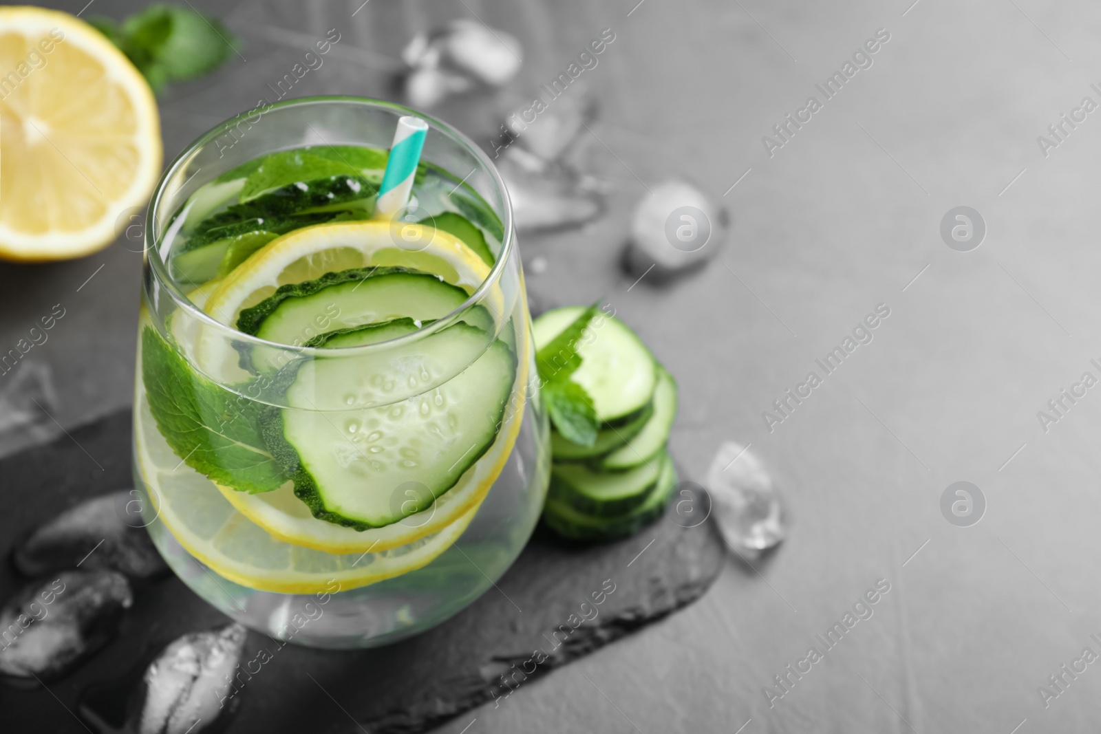 Photo of Refreshing water with cucumber, lemon and mint on black table. Space for text