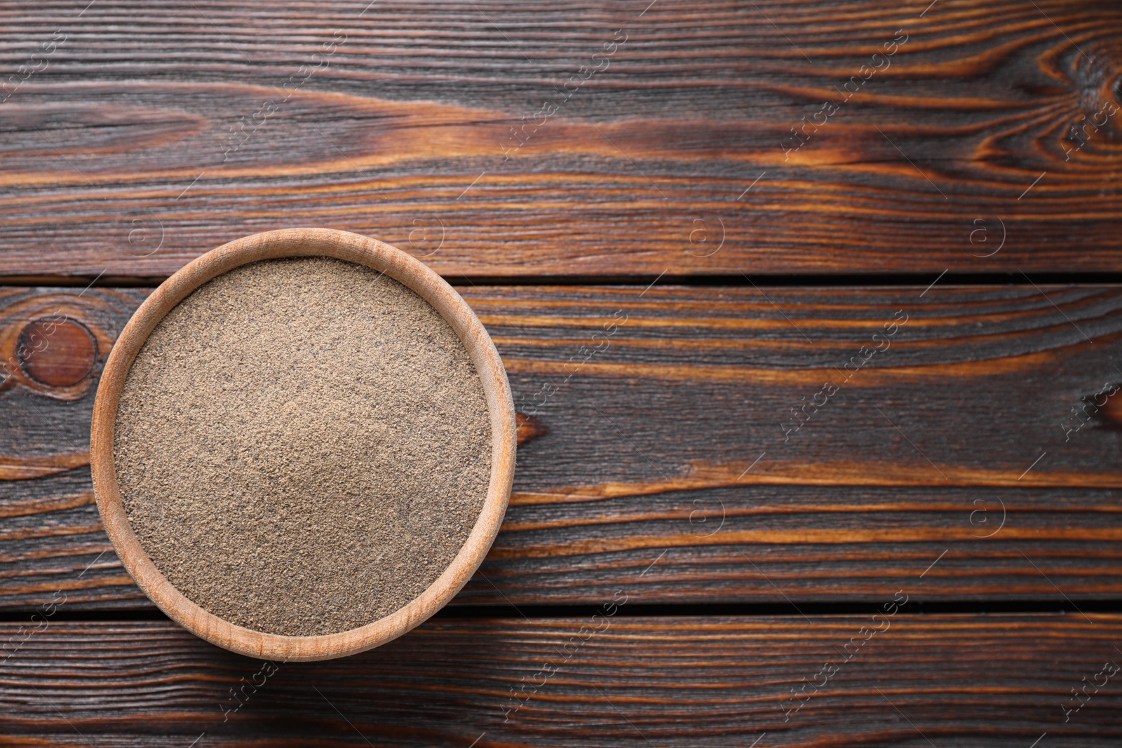 Photo of Ground black pepper on wooden table, top view. Space for text