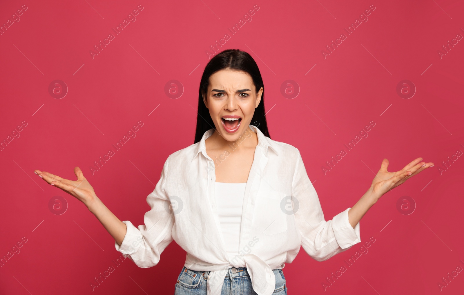 Photo of Angry young woman on pink background. Hate concept