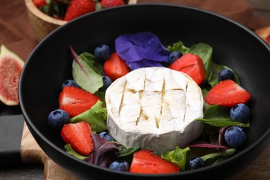 Photo of Delicious salad with brie cheese, blueberries and strawberries on table