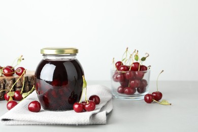 Photo of Jar of pickled cherries and fresh fruits on light table