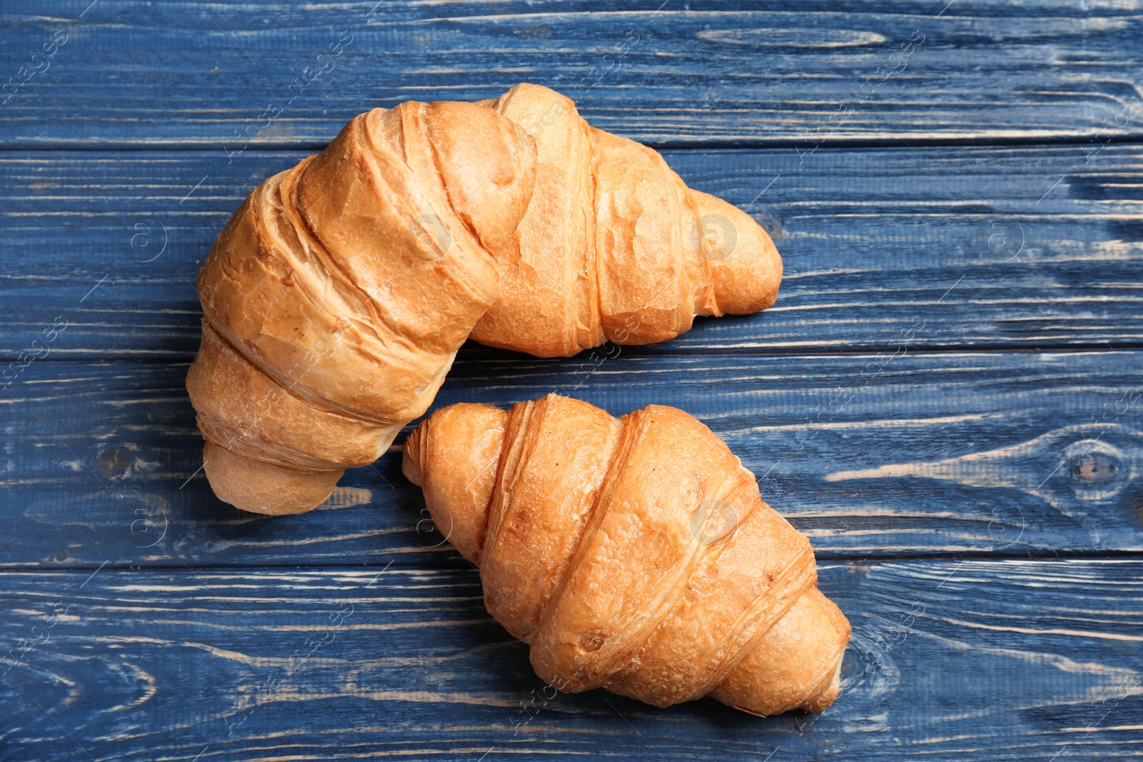 Photo of Tasty croissants on wooden background, top view