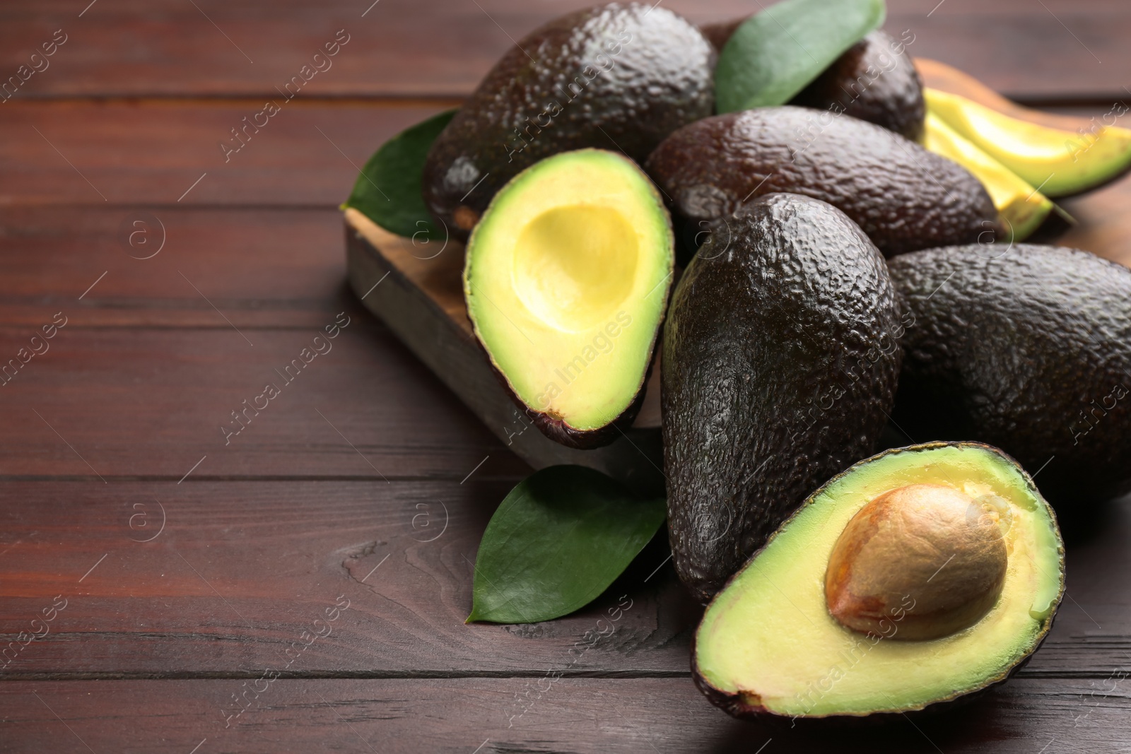 Photo of Whole and cut avocados on wooden table. Space for text