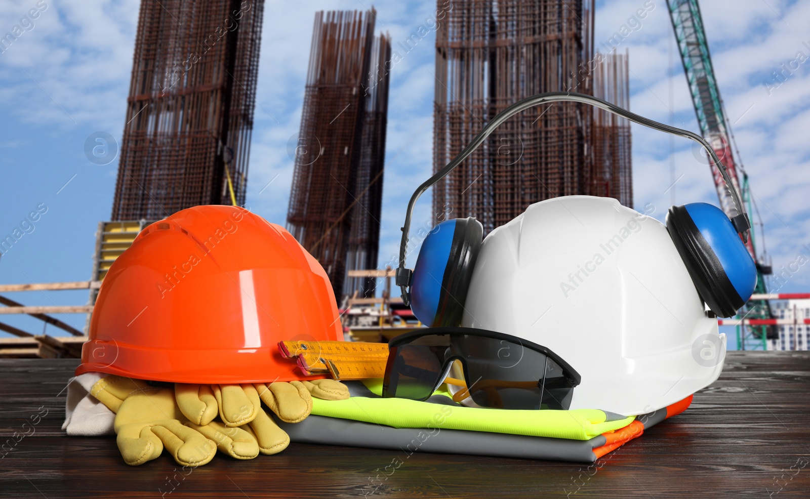 Image of Safety equipment and tools on wooden surface and blurred view of construction site