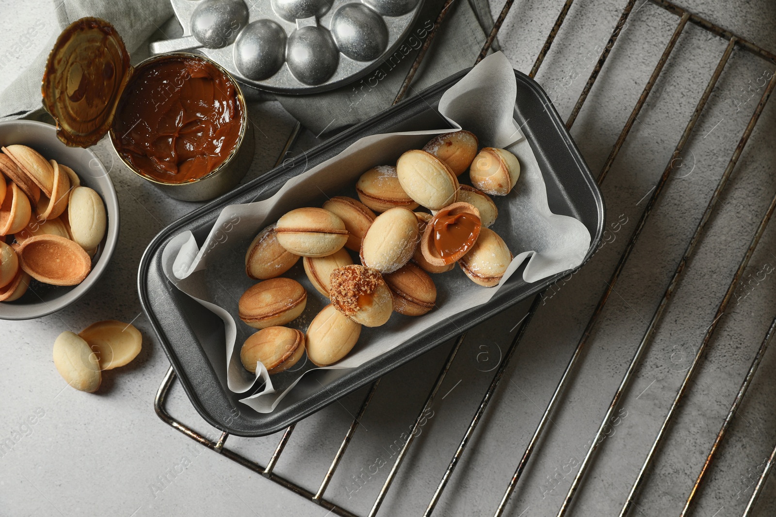 Photo of Delicious walnut shaped cookies with condensed milk on grey table, flat lay