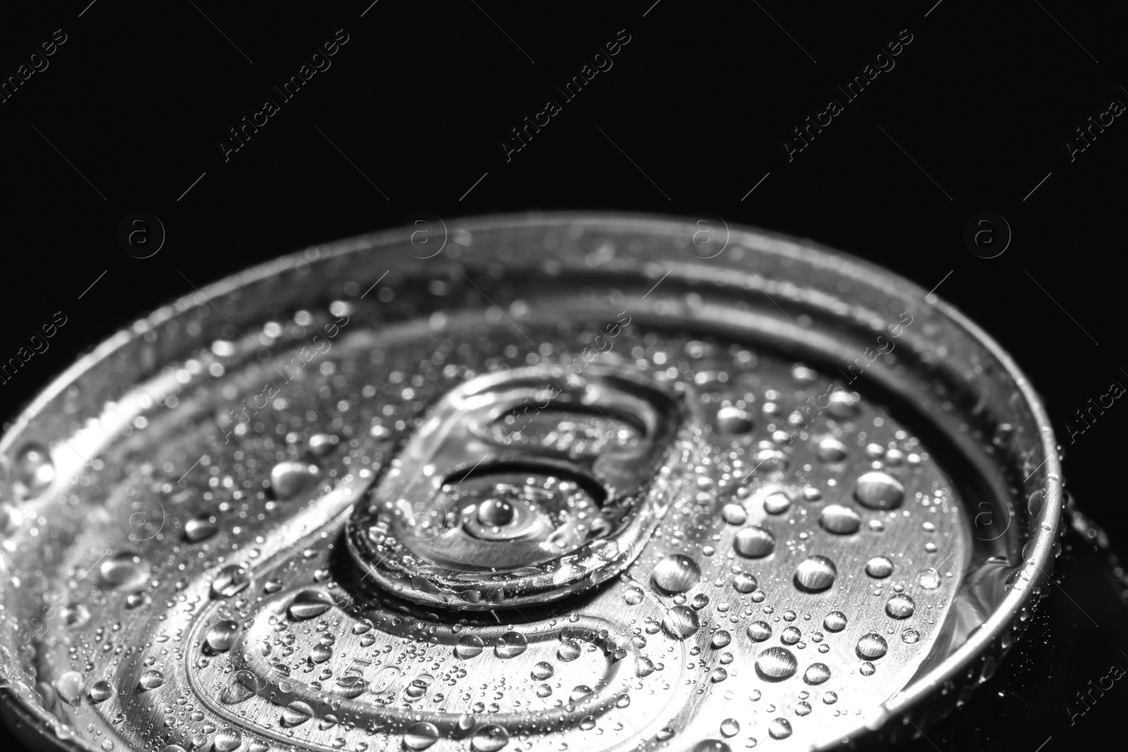 Photo of Aluminum can of beverage covered with water drops on black background, closeup