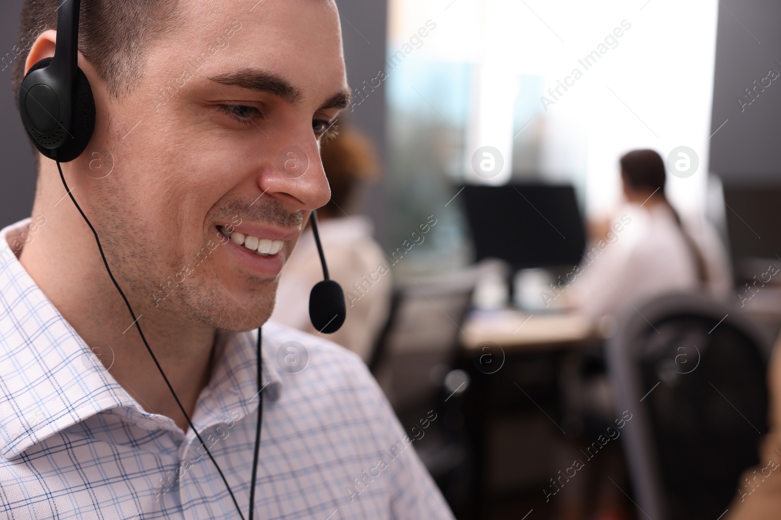 Photo of Young call center operator with headset working in modern office, closeup
