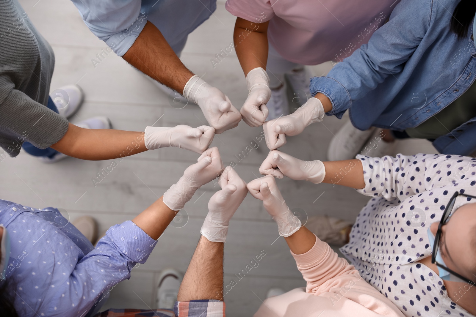 Photo of Group of people in white medical gloves showing thumbs up indoors, top view