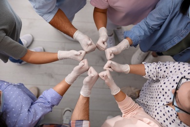 Photo of Group of people in white medical gloves showing thumbs up indoors, top view