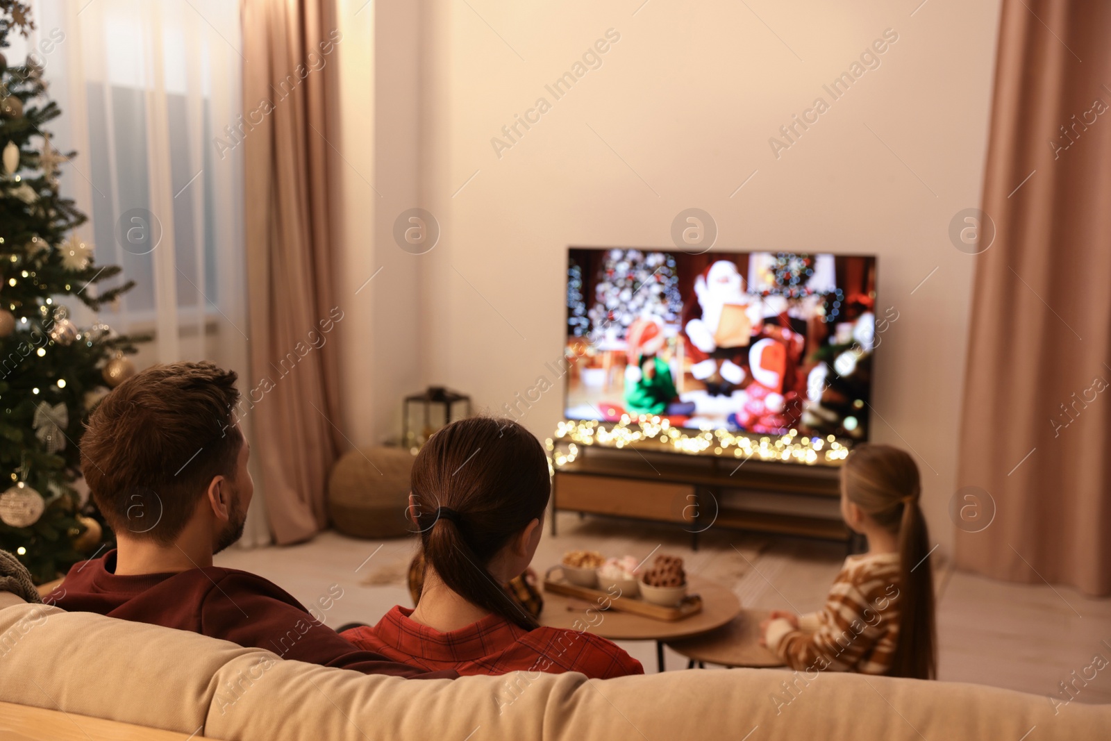 Photo of Family watching TV in cosy room. Christmas atmosphere