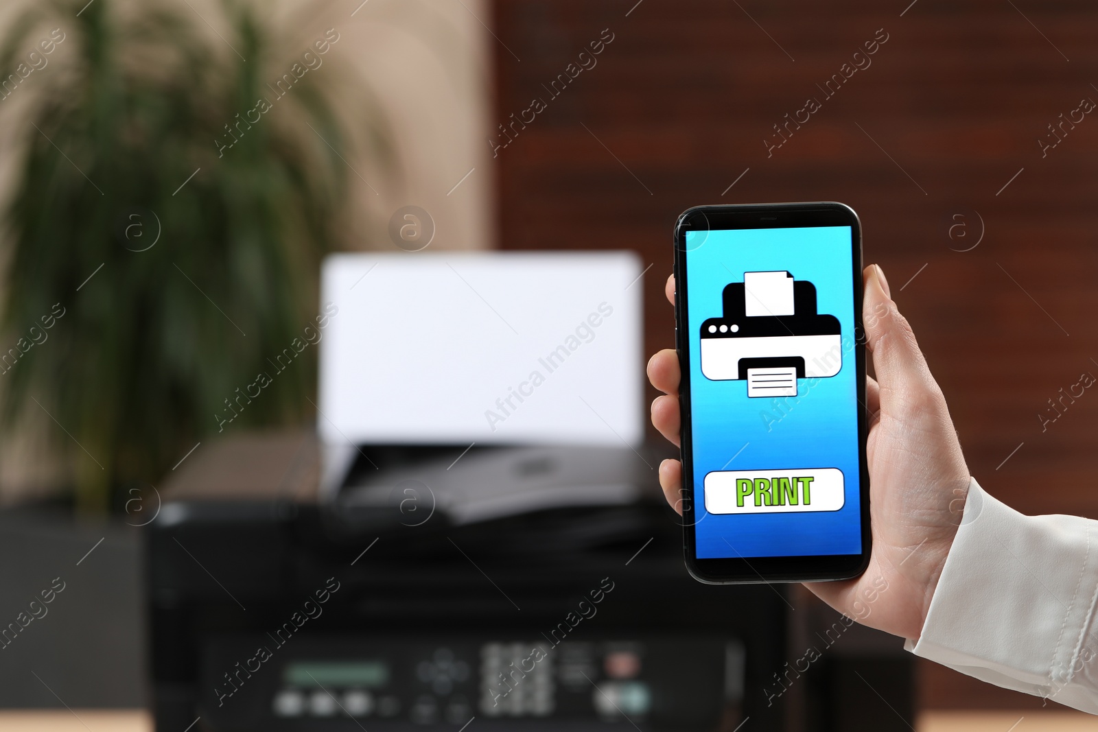 Photo of Man using printer management application on mobile phone in office, closeup and space for text