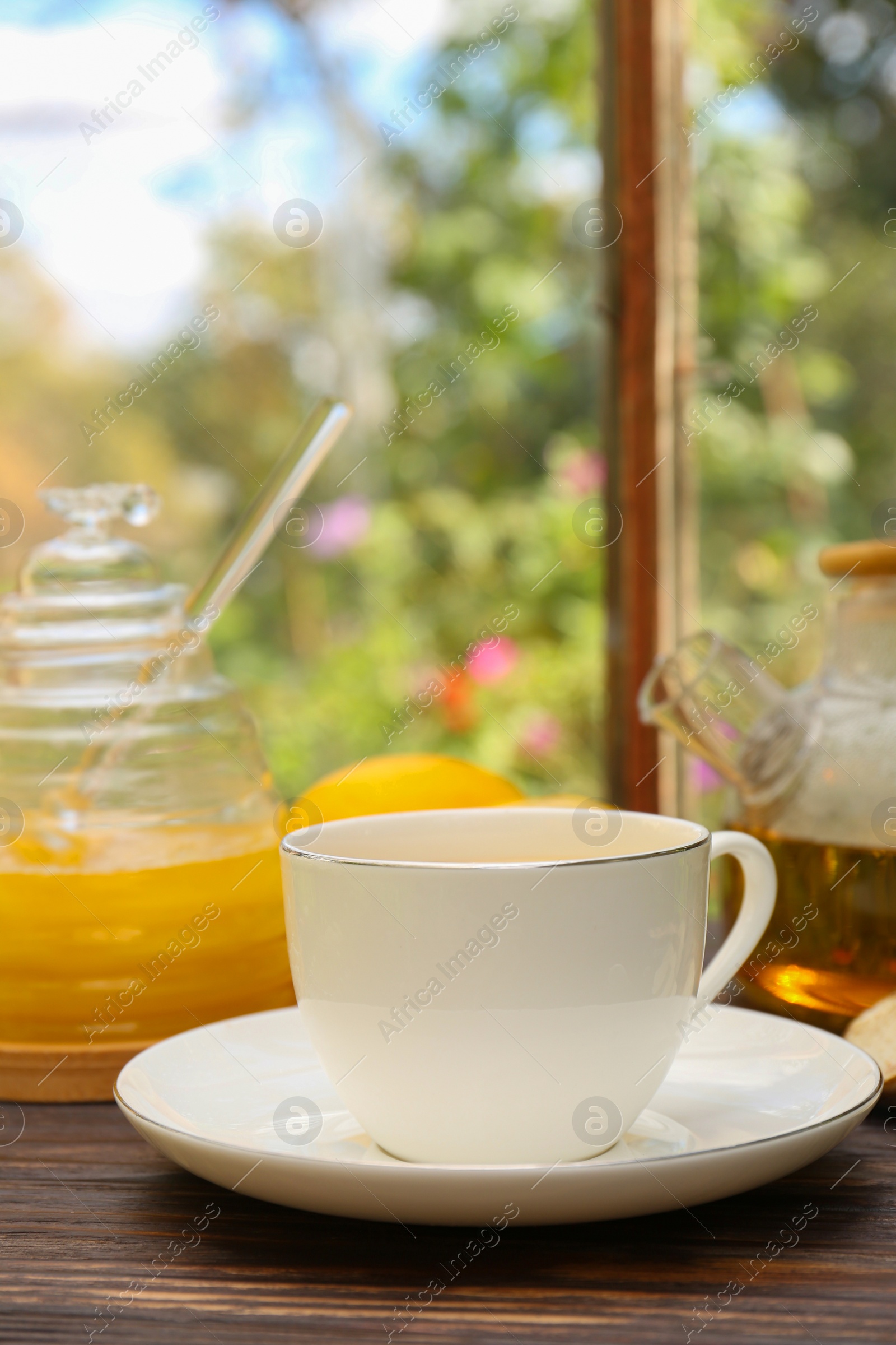 Photo of Cup of delicious tea with lemon and honey on wooden table