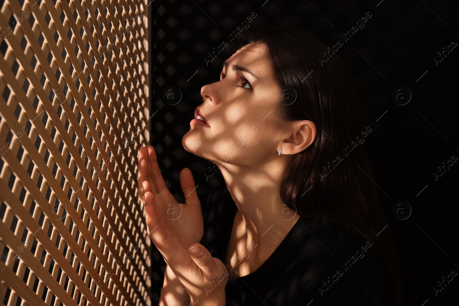 Photo of Woman praying to God during confession in booth