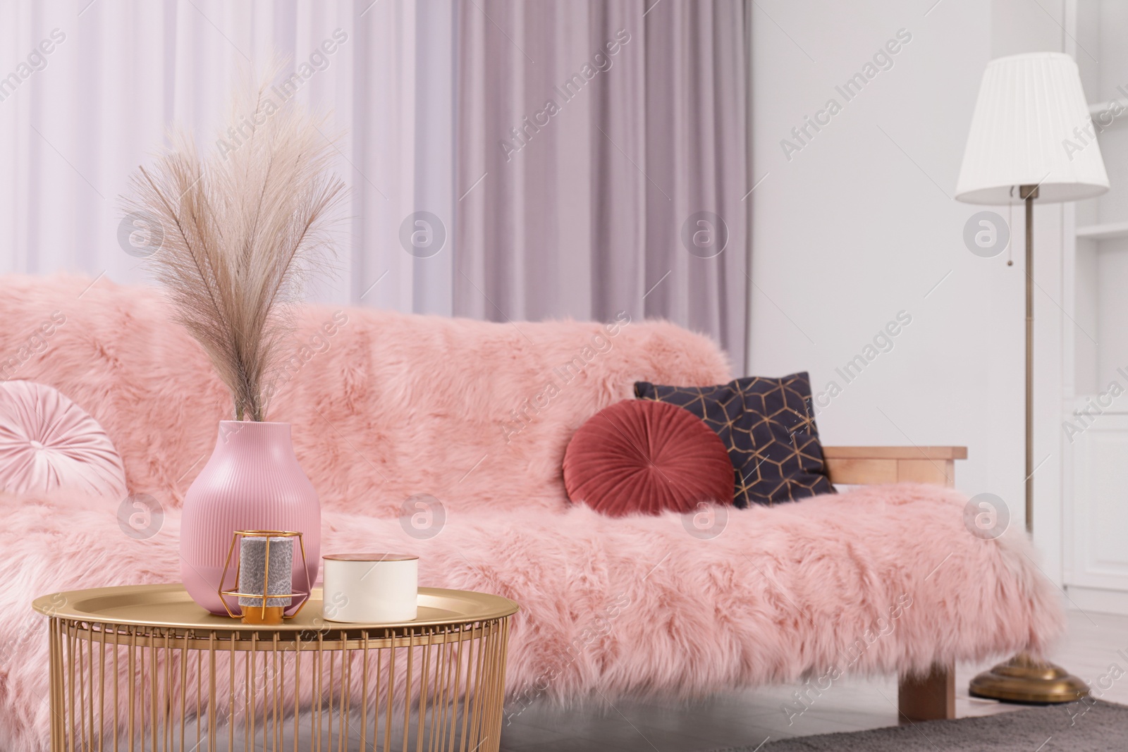 Photo of Vase and candles on coffee table near sofa in stylish room. Interior design