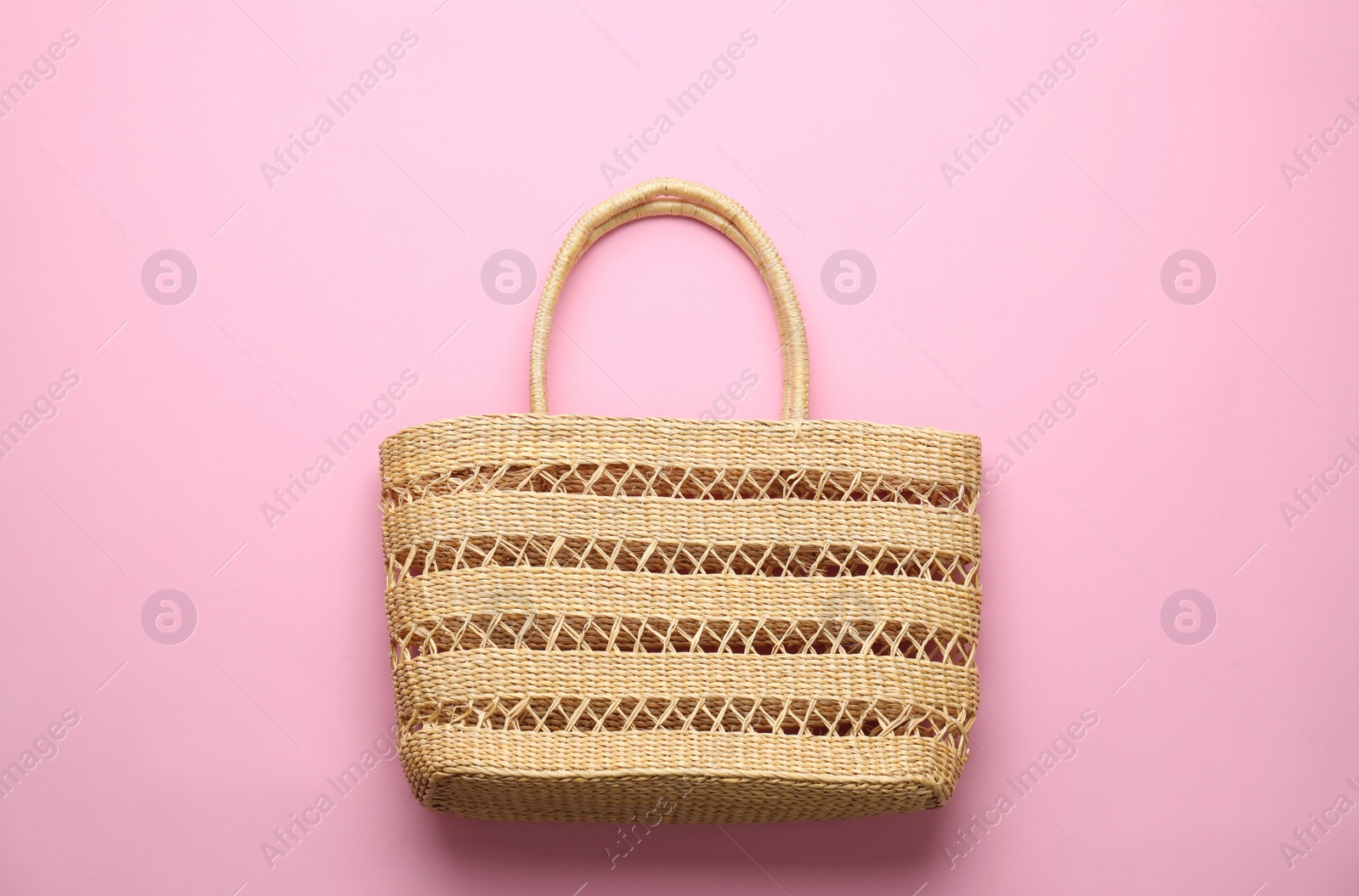 Photo of Elegant woman's straw bag on pink background, top view