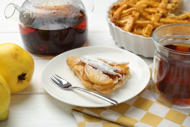 Piece of tasty homemade quince pie with powdered sugar served on white wooden table