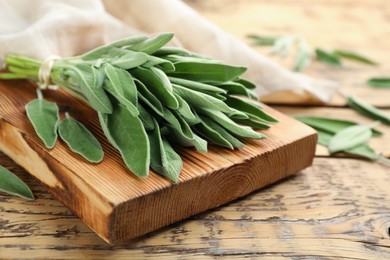 Photo of Board with fresh green sage on wooden table, closeup