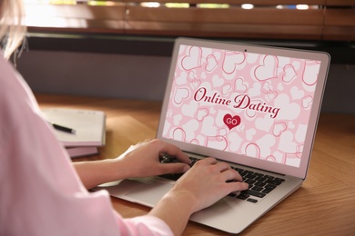 Woman visiting dating site via laptop at table, closeup