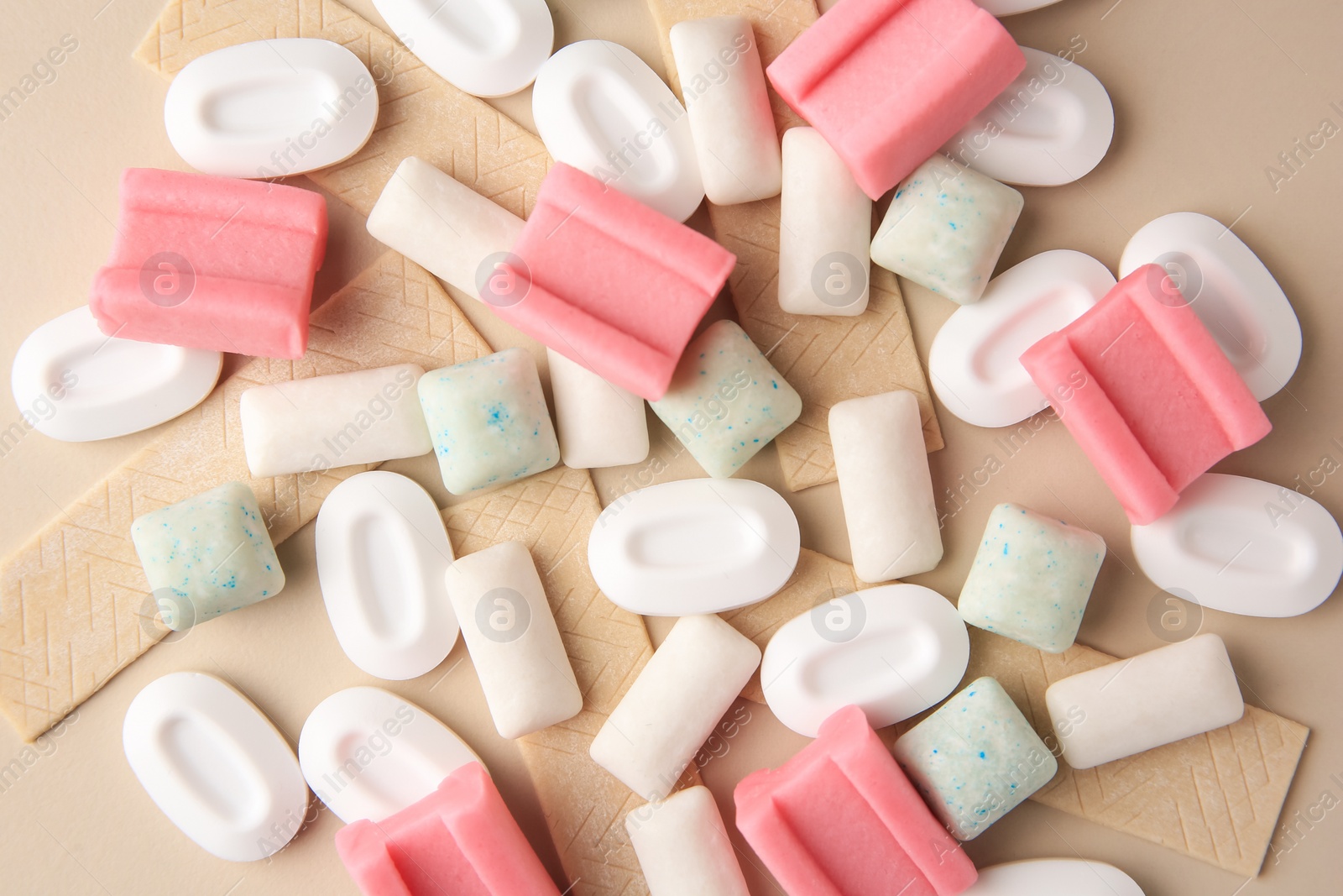 Photo of Many different chewing gums on beige background, flat lay