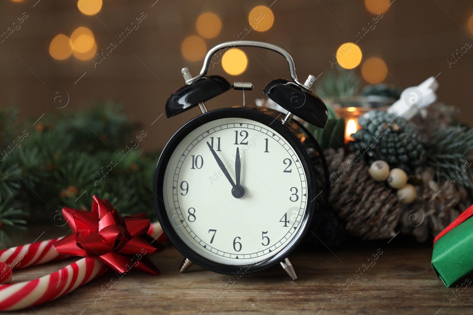 Photo of Vintage alarm clock and decor on wooden table against blurred Christmas lights, closeup. New Year countdown