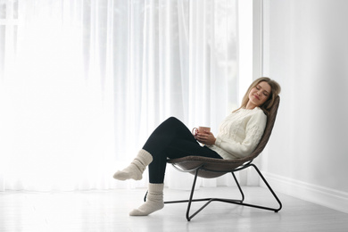 Young woman resting in armchair at home. Space for text