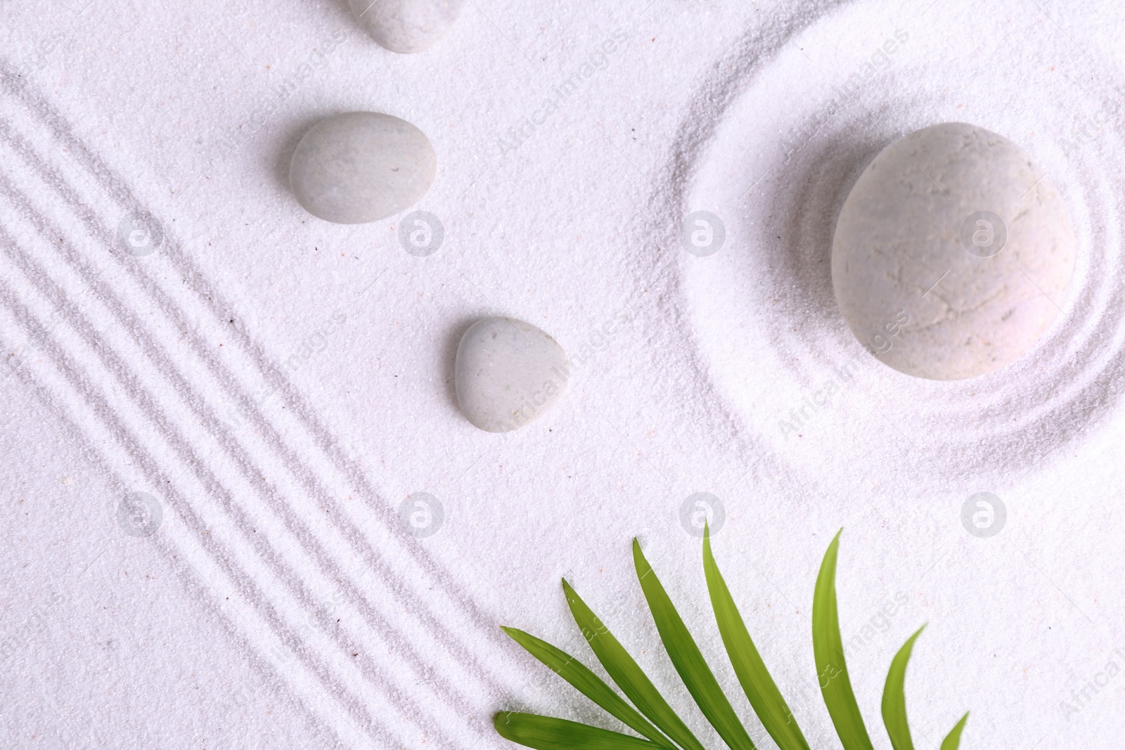 Photo of Zen garden stones and green leaves on white sand with pattern, flat lay