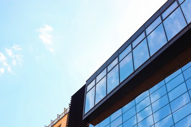 Photo of Low angle view of modern building with tinted windows against blue sky