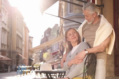 Photo of Affectionate senior couple sitting in outdoor cafe, space for text