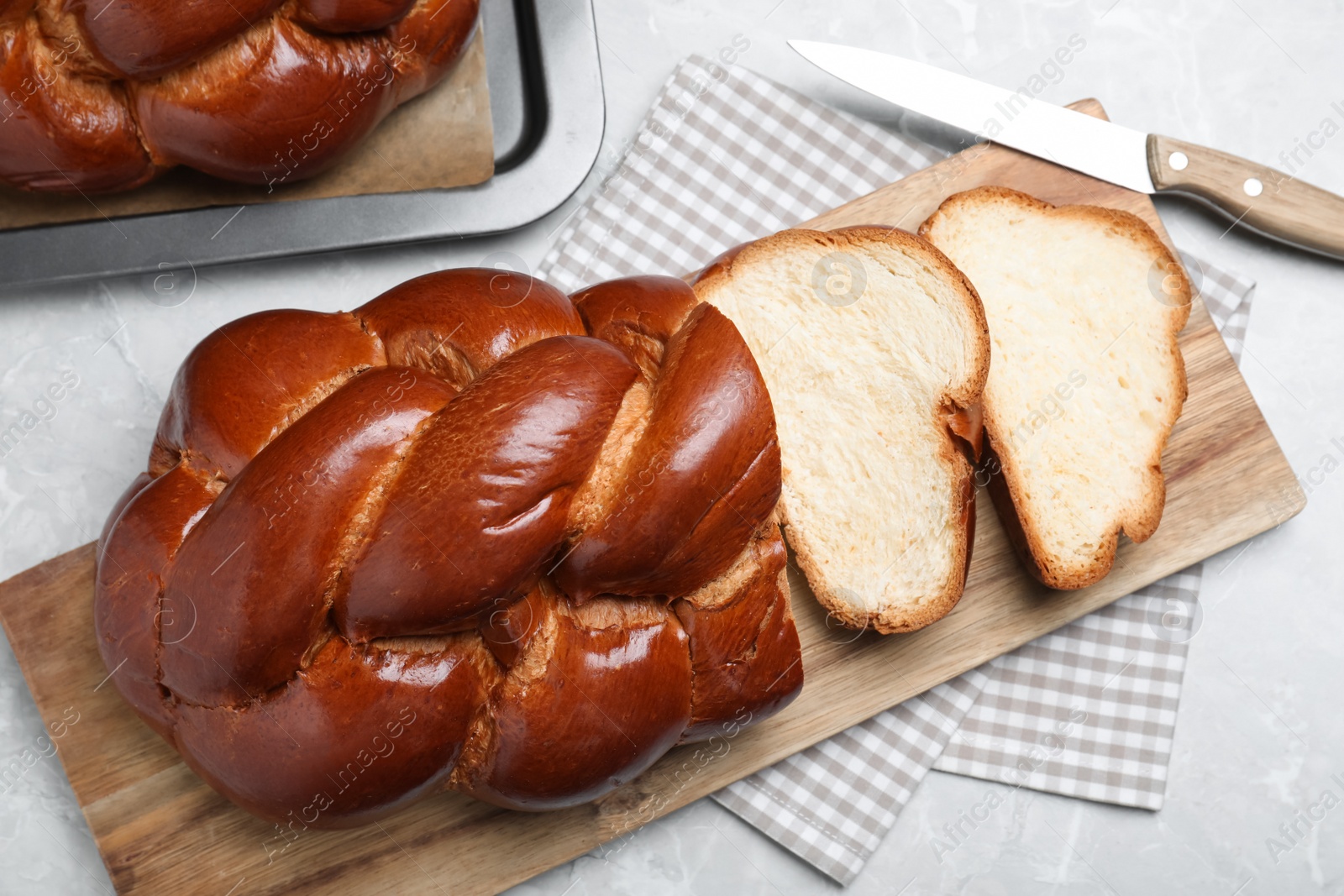 Photo of Cut homemade braided bread on grey table, flat lay. Traditional Shabbat challah