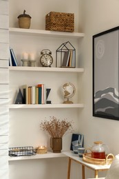 Books, alarm clock and different decor on shelves in room. Interior design