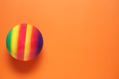 Photo of New bright kids' ball on orange background, top view. Space for text