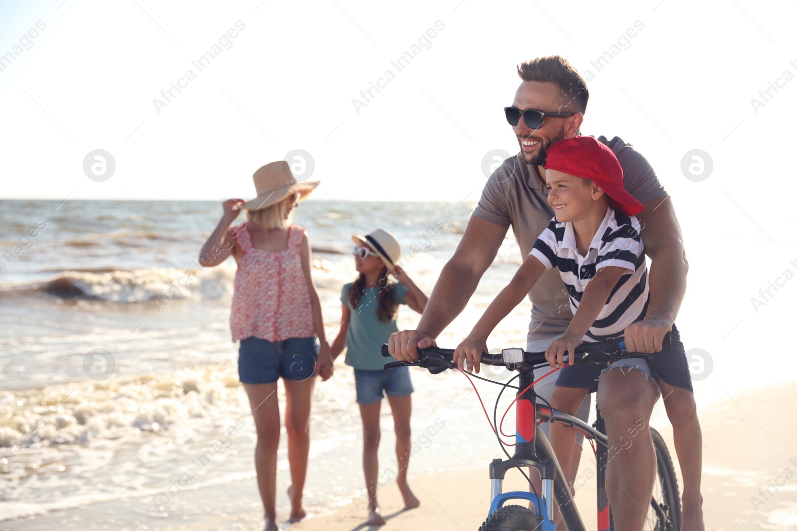 Photo of Happy family with bicycle on sandy beach near sea