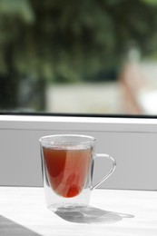 Glass cup of tea on wooden window sill