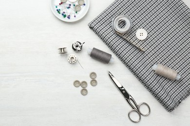 Photo of Flat lay composition with different sewing supplies and fabric on white wooden table. Space for text