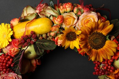 Photo of Beautiful autumnal wreath with flowers, berries and fruits on black background, closeup