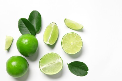 Photo of Fresh ripe limes and leaves on white background, flat lay. Space for text