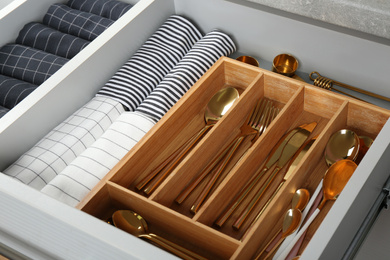 Photo of Open drawer with different utensils and folded towels. Order in kitchen