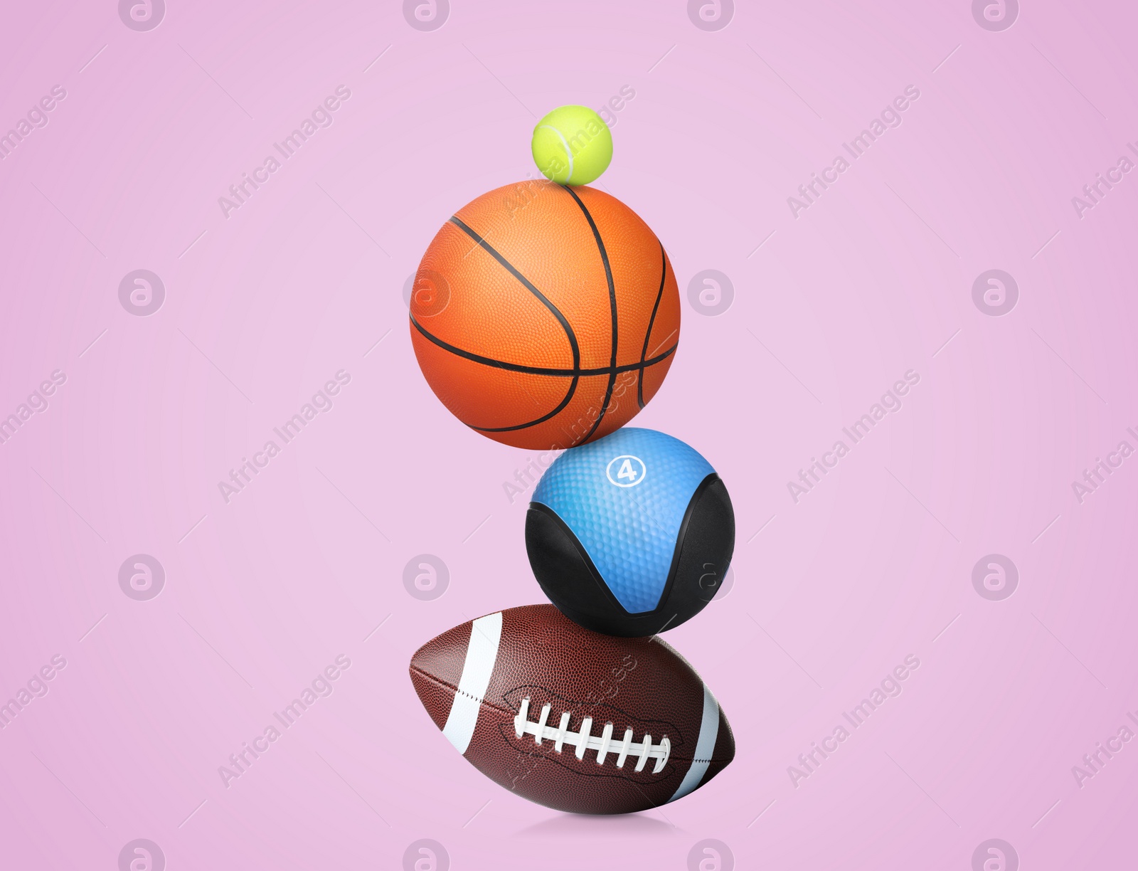 Image of Stack of different sport and medicine balls on light violet background