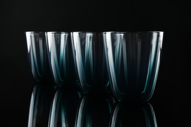 Set of empty colorful glasses on black background