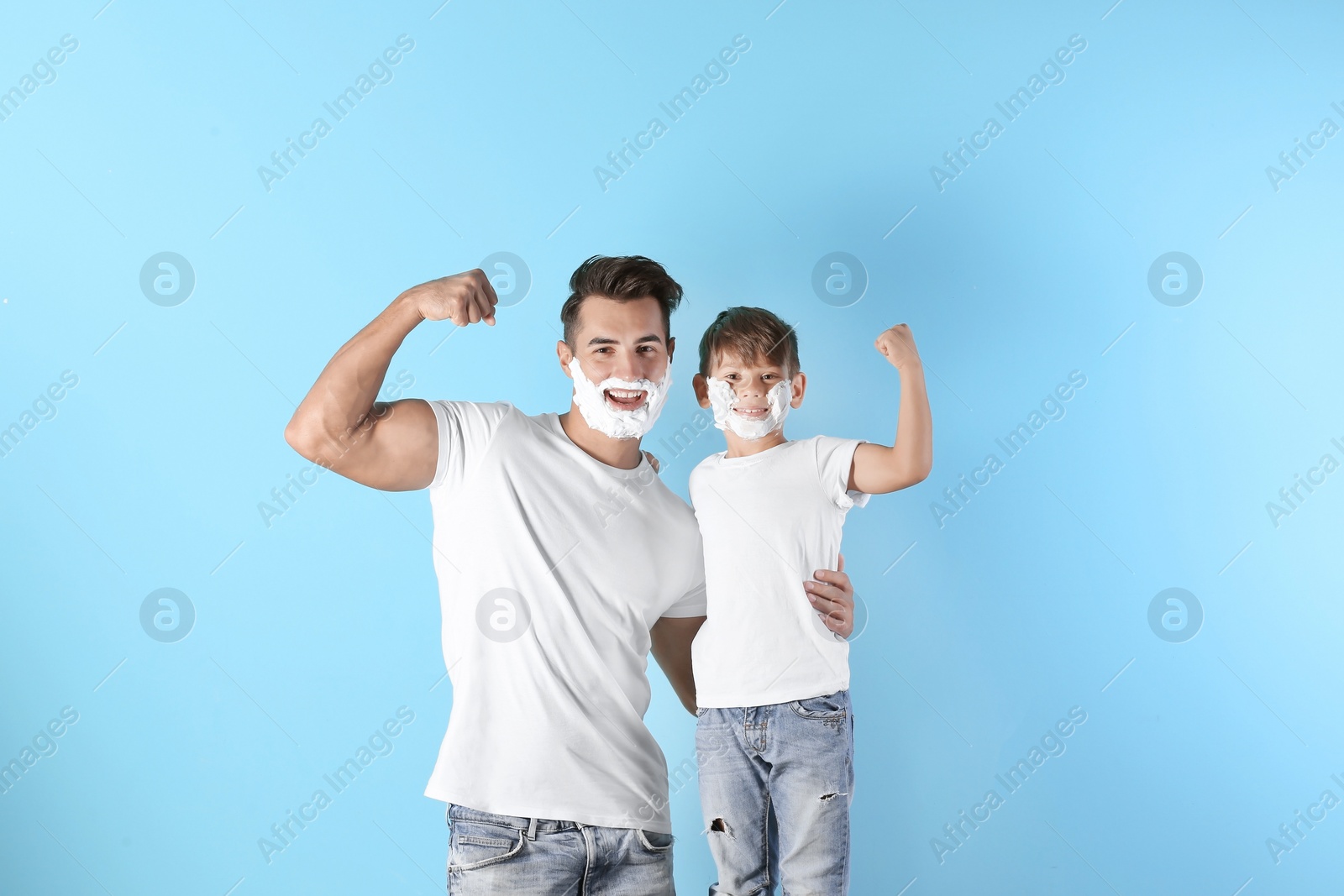 Photo of Father and son with shaving foam on faces against color background