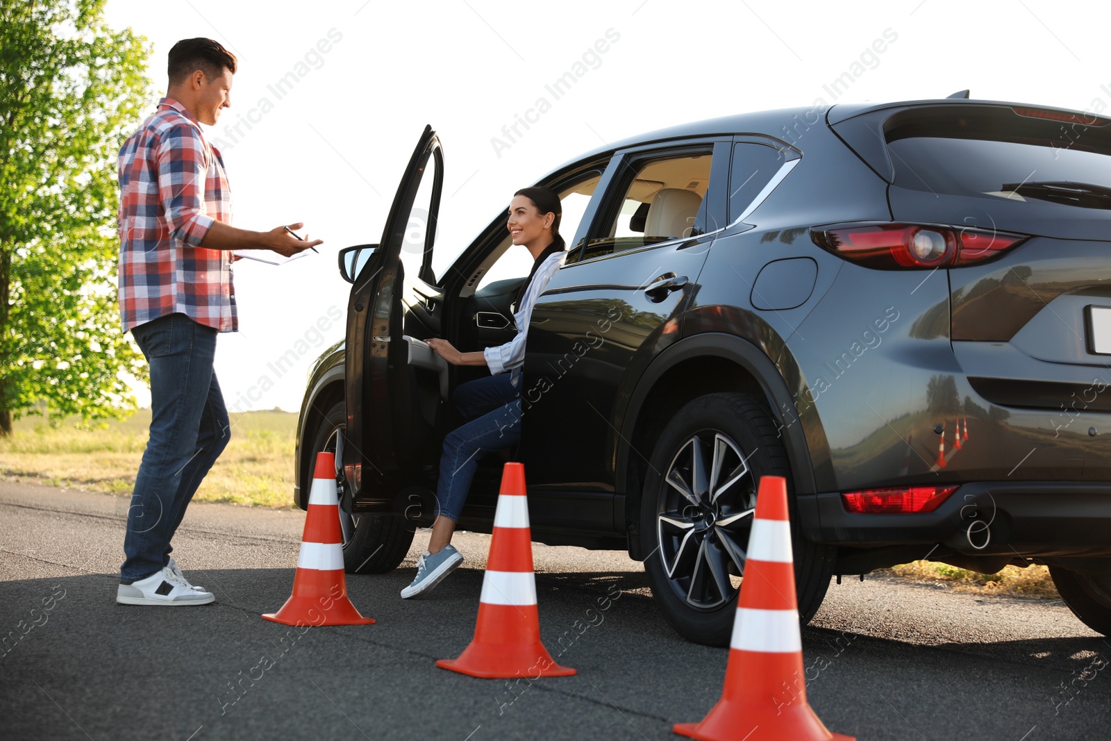 Photo of Instructor near car and his student outdoors. Driving school exam