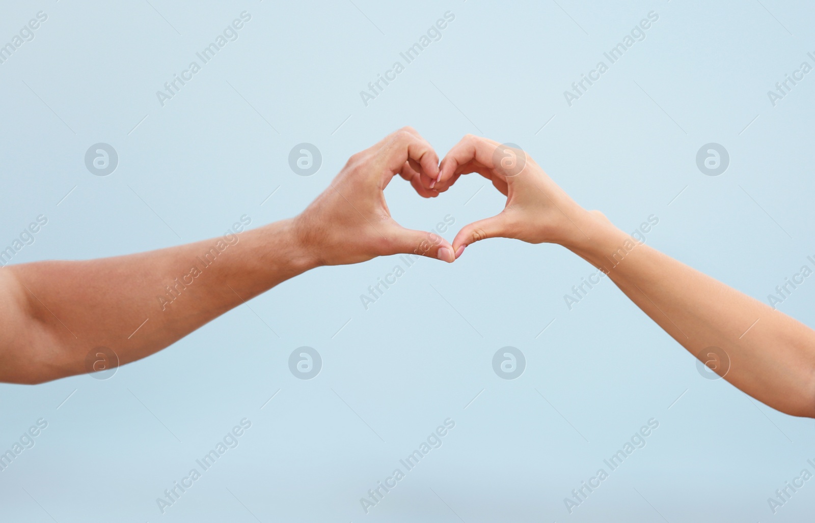 Photo of Happy couple making heart with their hands against blurred landscape