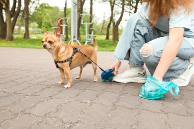 Photo of Woman picking up her dog's poop in park, closeup