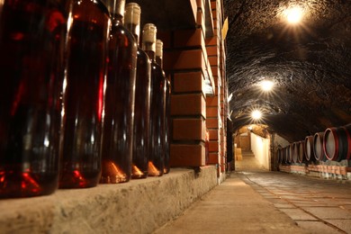 Photo of Beregove, Ukraine - June 23, 2023: Many bottles of alcohol drinks on shelves in cellar, low angle view