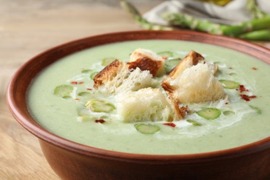 Photo of Delicious asparagus soup with croutons in bowl on table, closeup