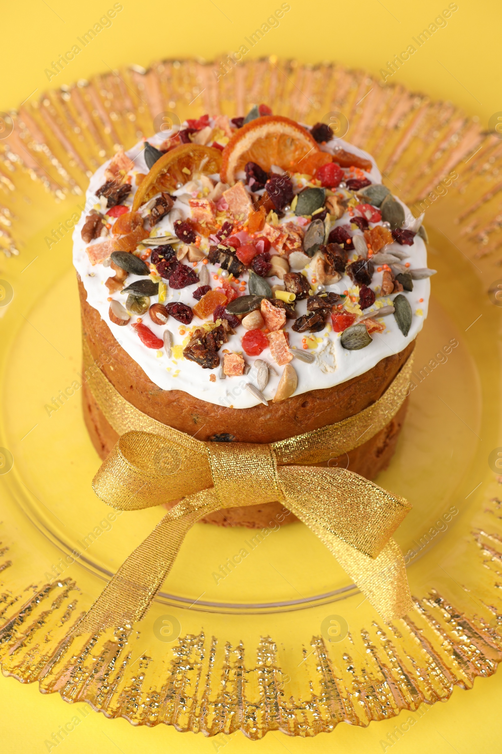 Photo of Traditional Easter cake with dried fruits on yellow background