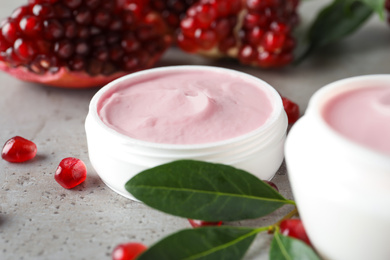 Natural facial mask, pomegranate seeds and green leaves on light grey table, closeup