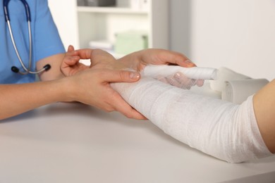 Photo of Doctor applying bandage onto patient's arm in hospital, closeup