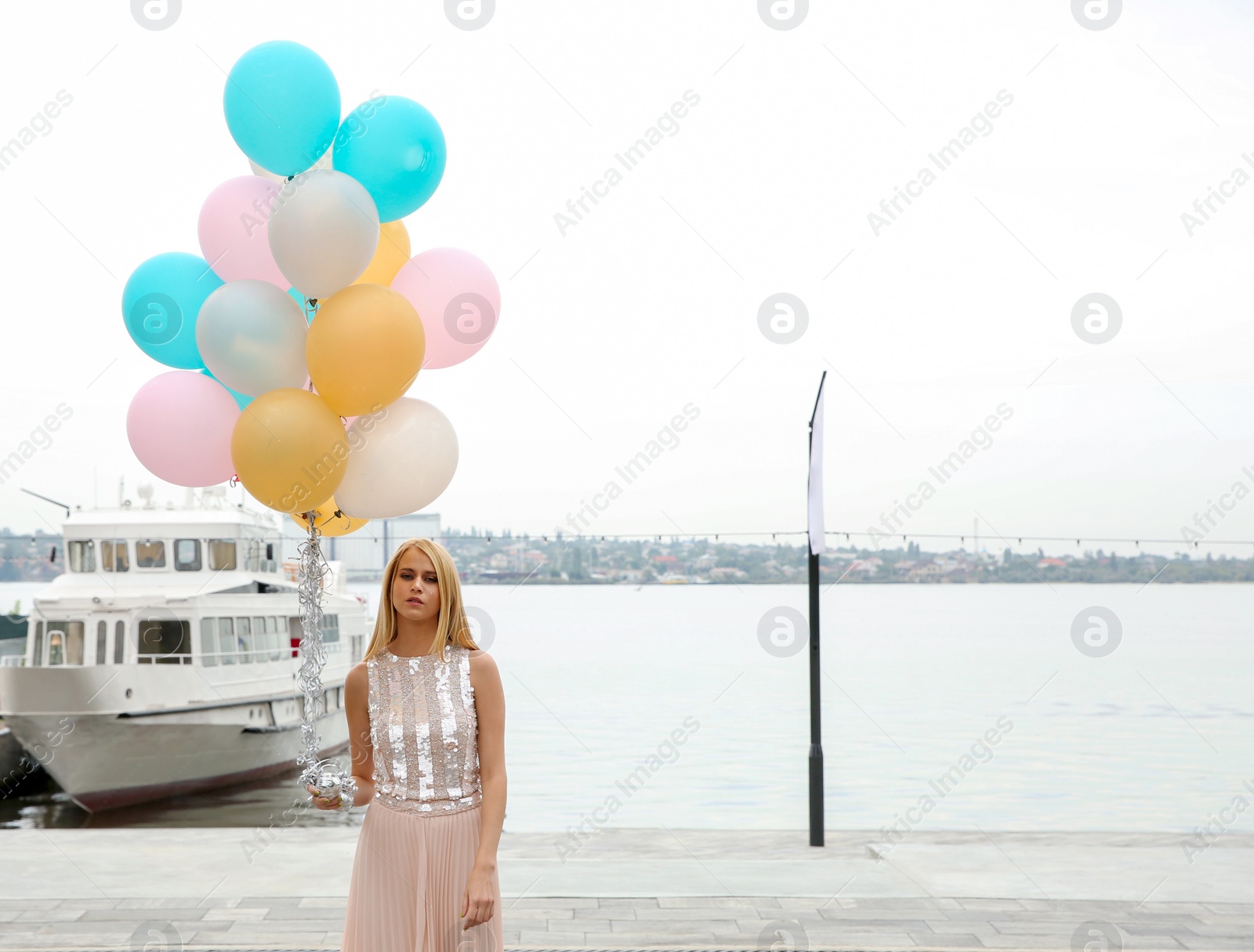 Photo of Beautiful young woman with bunch of balloons outdoors. Space for text