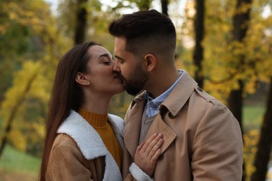 Photo of Happy young couple kissing in autumn park